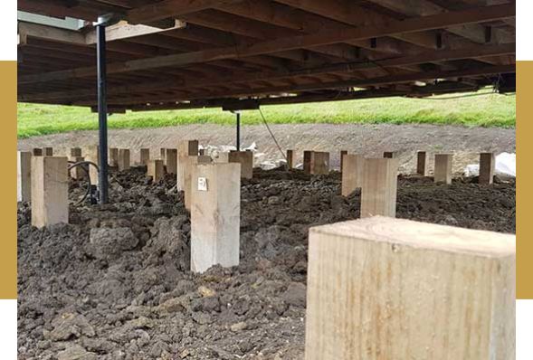 A house raised on hydraulic jacks with the old timber piles exposed underneath