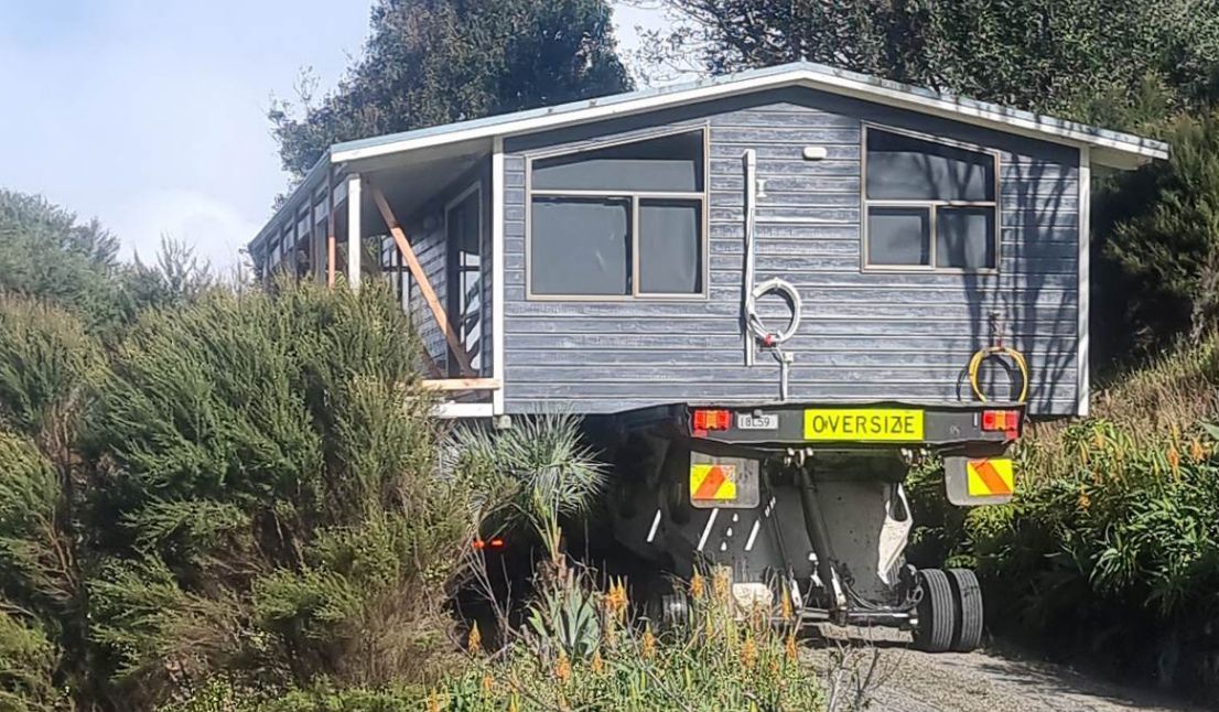 A relocated house being manoeuvred onto a prepared site